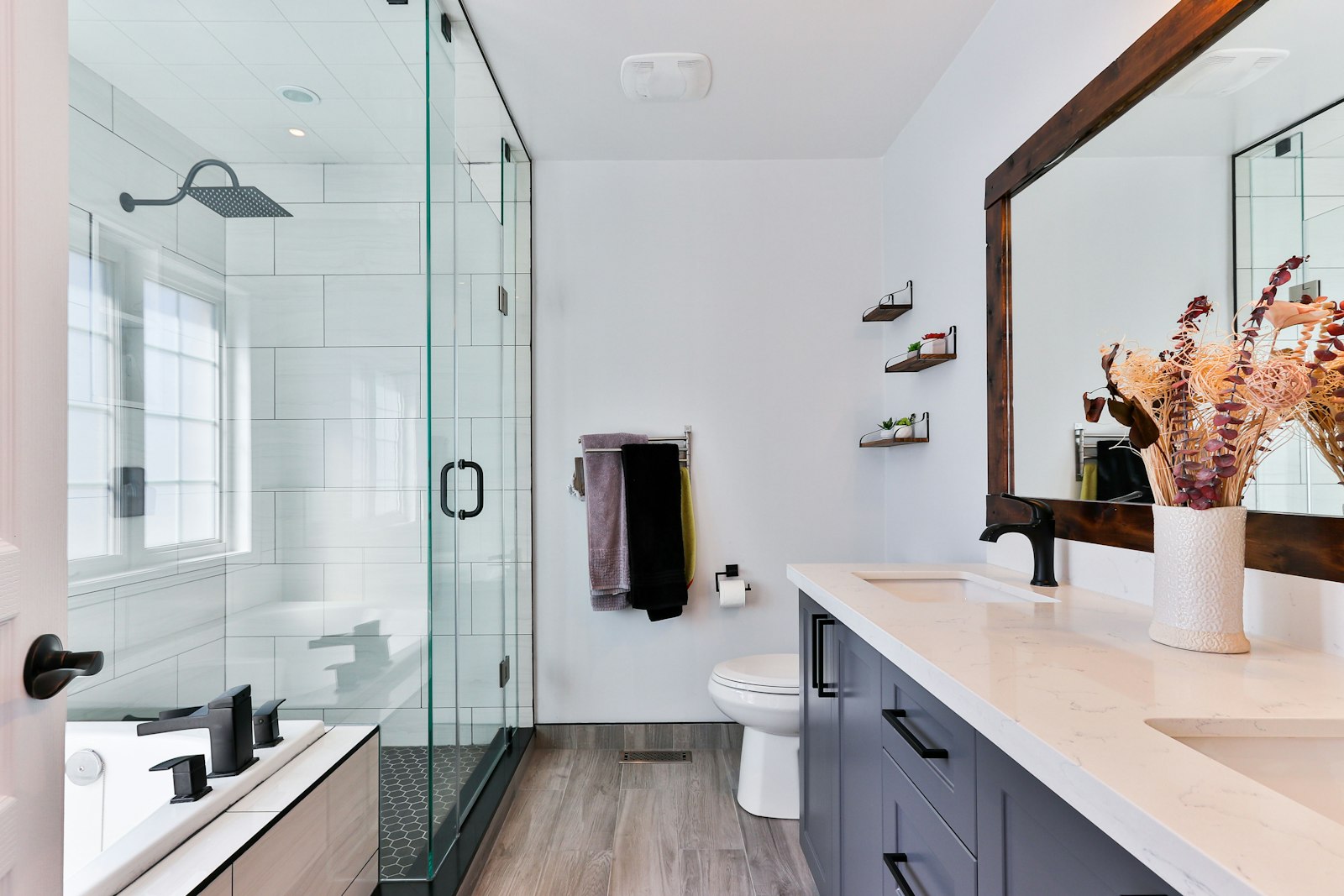 Bathroom after — quartz, glass enclosure, dark fixtures